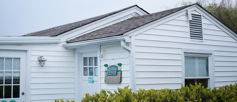 white duplex building surrounded with green shrubbery aqua welcome sign on office door