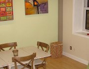 dining area with white table and four tan chairs next to a green side chair.