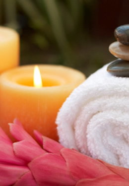 massage-therapy towel and candles with meditation stones and pink flower