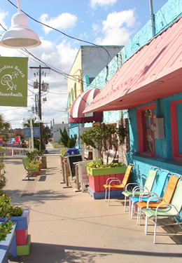 view of boardwalk with blue green and salmon flower boxes and chairs green flags flying