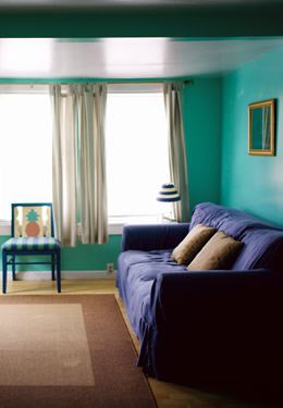 cottage one living room with blue couch, striped blue and green chair with pineapple design on the back and tv