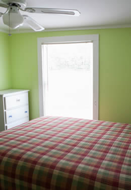 plaid blanket covering a queen size bed.  Lime green walls and a dark green curtain along the back wall