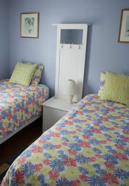 room with two twin bed, blue painted walls, window with white blinds and bamboo style laminate flooring