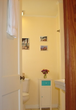 white bathroom door open with showing and a small dresser with a aqua blue drawer and blue knobs